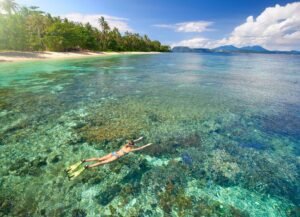 A Girl Swimming In The Sea With Island Near Her