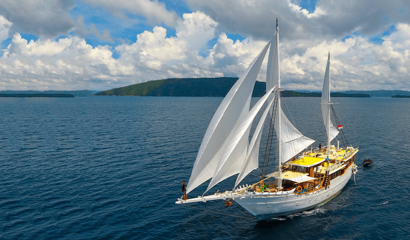 The Teman Liveaboard sailing in Komodo with guests enjoying the view from the bow.